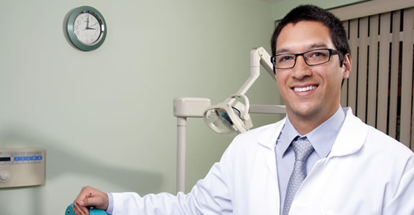 Picture of a dentist, representing all dentists in San Jose, Costa Rica.  The picture is a close-up picture of a male dentist smiling at the camera.